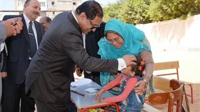 محافظ الغربية يداعب طفلة أمام إحدى اللجان في انتخابات الرئاسة المصرية 2018